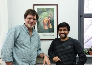 פרופ' מיכאל גליקמן (משמאל) וד"ר אינדרג'יט סהו מהפקולטה לביולוגיה בטכניון. בין השניים תלוי ציור של ד"ר סהו ובו מוצג פרח הכדנית.
