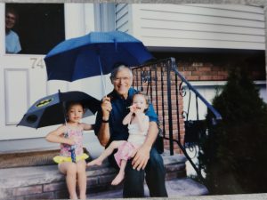 מתחת למטריה: רינה (משמאל) ואחותה עם סבא בנימין. סבתא מיירה מציצה מהחלון שבדלת