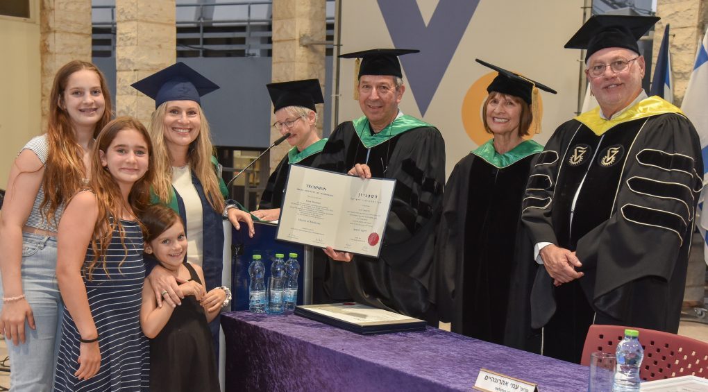 Dr. Dana Shoshani-Dror, accompanied by her three children, receives her degree from the Dean of the Rappaport Faculty of Medicine, Prof. Ami Aronheim, at this week’s graduation ceremony