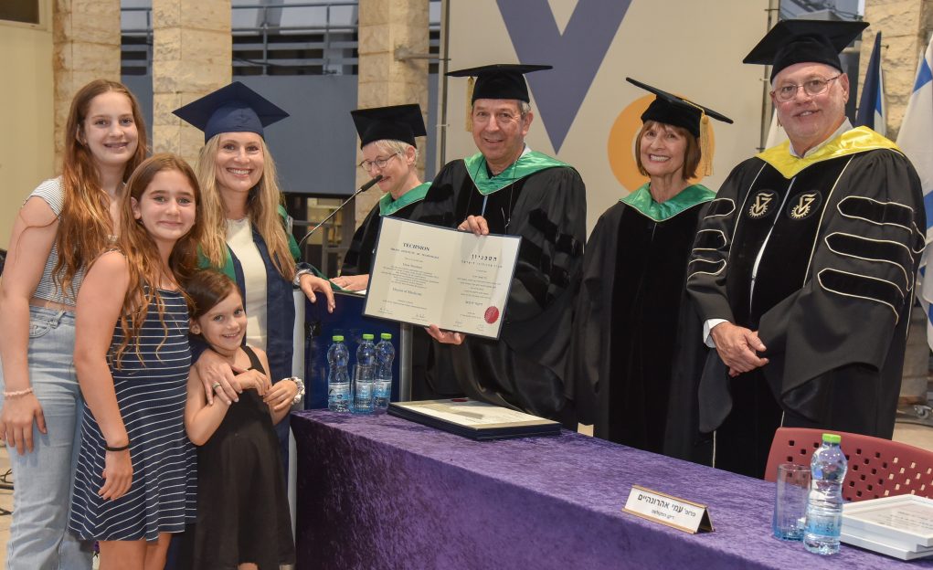 Dr. Dana Shoshani-Dror, accompanied by her three children, receives her degree from the Dean of the Rappaport Faculty of Medicine, Prof. Ami Aronheim, at this week’s graduation ceremony