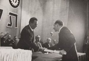 בתמונה ההיסטורית: מישקין (מימין) לוחץ יד עם ראש עיריית חיפה, אבא חושי, בעת קבלת התעודה.