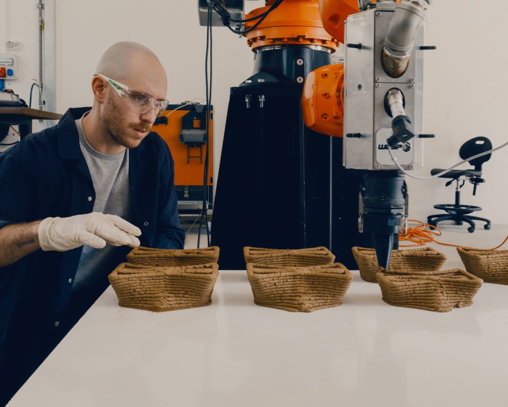 Doctoral student Ofer Asaf, during robotic 3D printing, examines the accuracy and texture of the printed bricks made from the local soil mixture.